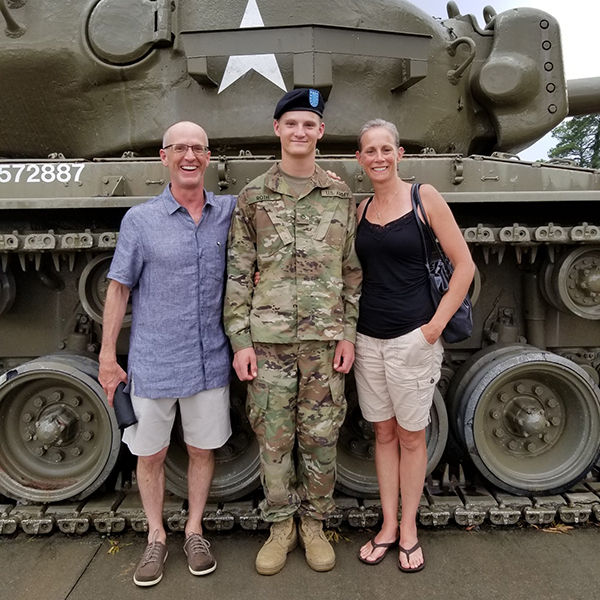 Family posing in front of a tank