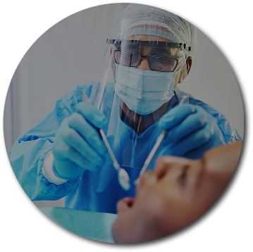 A dentist in full protective gear examines a patient using dental tools. The setting is clinical, conveying professionalism and care.